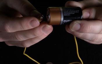 hands holding a wire and battery